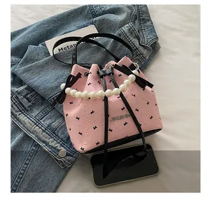 Détail du sac seau rose avec motif nœud, poignée en perles et cordons