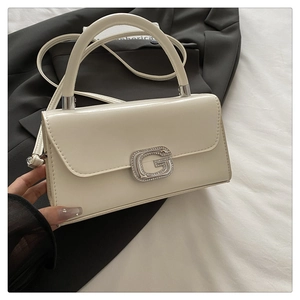 Close-up of white rectangular handbag with diamond G-buckle on black suit jacket