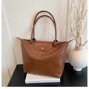 Close-up of brown textured leather tote bag featuring a gold snap button and top flap