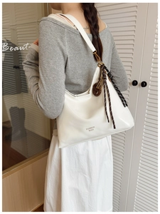 Détail du sac hobo blanc en demi-lune avec boucle marron et pampille tissée décorative