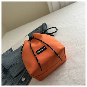 Detail of orange nylon bucket bag with Creative Cat label and woven drawstring closure