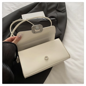 Detail view of the white flap handbag showing silver magnetic closure and interior space