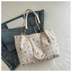 Detail of printed tote bag featuring strawberry and teddy bear patterns with pearl chain