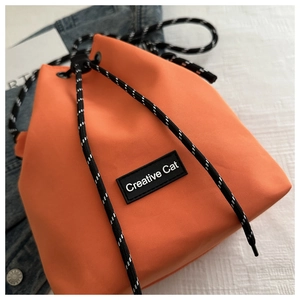 Top view of orange nylon drawstring bucket bag with Creative Cat label and woven cord