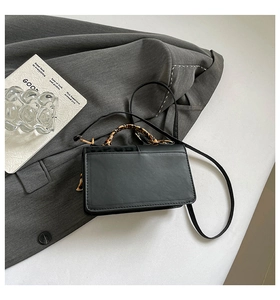 Detail of black leather handbag with leopard print flap and handle on suit fabric