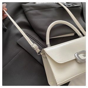 Detailed shot of white PU leather handbag featuring silver G-shaped rhinestone buckle decoration