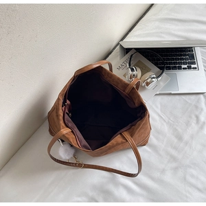 Interior detail of large brown suede tote bag showing zipper pocket and fabric lining