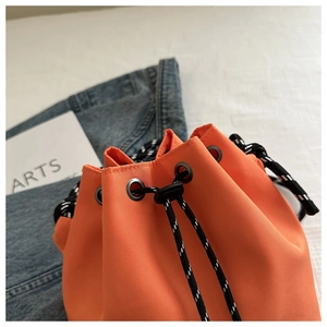 Detailed close-up of orange nylon bucket bag with drawstring closure and contrast strap