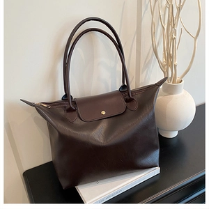 Detail view of coffee brown tote bag featuring fine texture and golden metal snap button