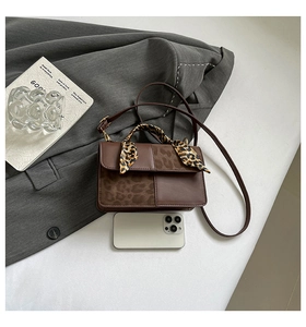 Brown leopard print crossbody bag detail with smartphone for scale on grey fabric