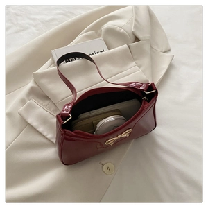 Detail view of burgundy patent leather bag with gold bow showing spacious interior storage