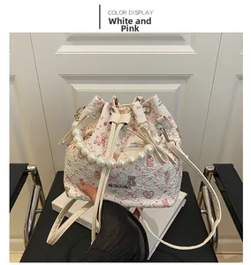 Détail du sac seau blanc et rose avec imprimés cartoon, poignée en perles et cordon serrage