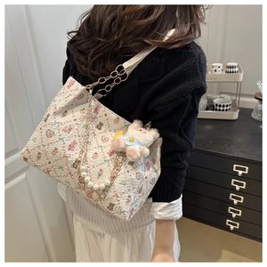 Close-up of floral bear print tote bag with pearl chain strap and plush bear charm