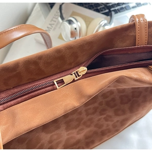 Detail of leopard print tote bag with premium golden zipper and soft suede texture
