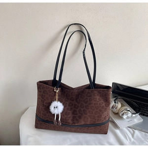 Close-up of leopard print tote bag with black straps and a white plush monster charm