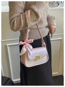 Detail of pink leather handbag with decorative silk ribbon bow and metal clasp buckle