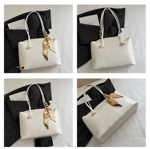 Détail du sac cabas blanc avec texture crocodile et foulard décoratif sur l'anse