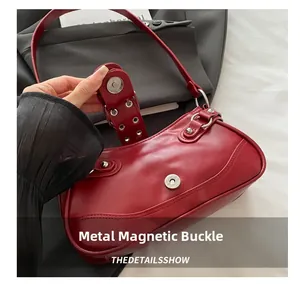 Detail of red leather moon bag showing silver magnetic snap closure and metal rivets