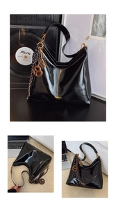 Détail du sac hobo en cuir brillant noir avec lettrage doré et pendentifs décoratifs