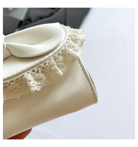 Close-up of white leather handbag with intricate lace trim and bow knot detail