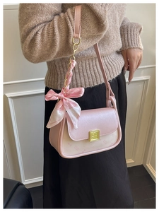 Detail of pink shoulder bag with metallic clasp and silk bow on high-quality leather