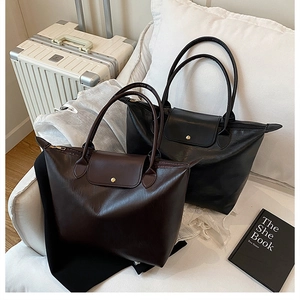 Detail of dark brown and black large capacity tote bags with smooth leather texture