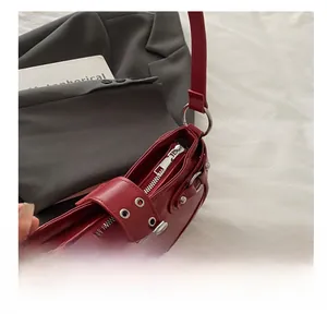 Detailed view of the smooth silver zipper and metallic buckle on the red leather handbag