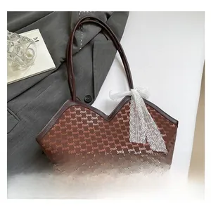 Détail du sac cabas monogramme marron avec un nœud en dentelle blanche et bord en cuir