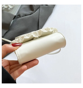 Detailed view of mini white crossbody bag with delicate embroidered lace trim detail
