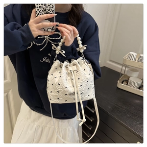 Détail du sac seau blanc avec broderies de nœuds noirs et poignée en perles