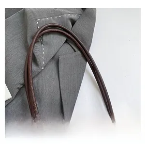 Détail des poignées en cuir marron et nœud en dentelle sur un cabas vintage monogramme