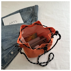 Detail view of bright orange nylon drawstring bucket bag with spacious inner storage
