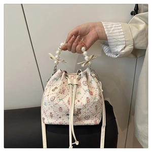 Détail du sac seau floral avec poignée en perles, nœud décoratif et imprimé d'ours