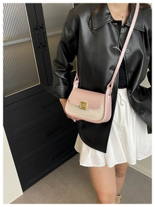 Detail of a pink and beige leather crossbody bag featuring a golden metal buckle
