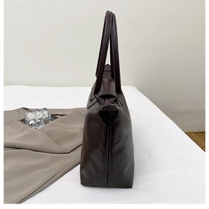 Side view of dark brown leather tote bag with long handles and zipper closure