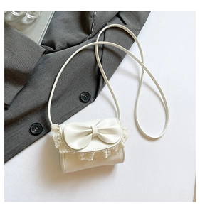 Detail of white balletcore crossbody bag with delicate lace edges and bow on grey blazer