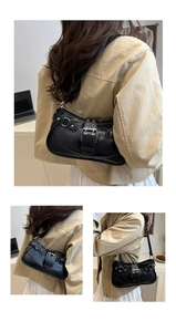 Detail of black faux leather shoulder bag with silver eyelets and punk metal buckle
