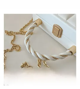 Detail of white quilted leather bag with woven gold chain handle and metal clasp