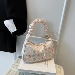 Chic white crescent bag with cute bear prints and pleated handle on a minimalist setup