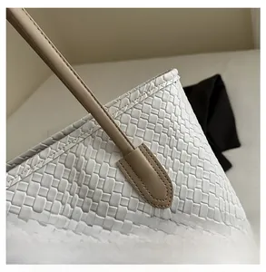 Close-up of cream woven faux leather tote bag with camel handle and neat stitching