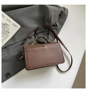 Detail of dark brown tote bag with suede texture flap and leopard print scarf on handle