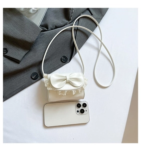 Detailed comparison of white lace bow mini bag size with a smartphone perspective