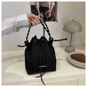 Detail of black drawstring bucket bag with Creative Cat label and woven rope handle