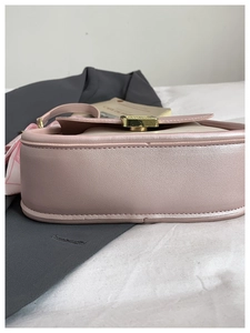 Detail shot of a pink shoulder bag showing side stitching and floral silk scarf strap