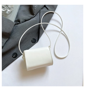 Detail of white mini crossbody bag with lace accents and slim shoulder strap