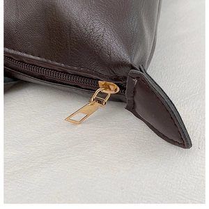 Detail of dark brown lychee grain leather texture with gold metal zipper closure