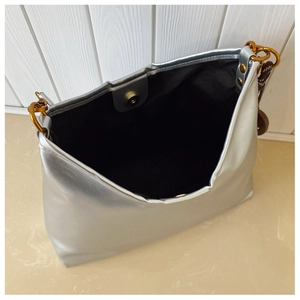 Vue détaillée du sac argenté avec fermoir magnétique doré et doublure noire interne