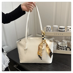 Dettaglio borsa tote beige con trama coccodrillo e foulard elegante sui manici