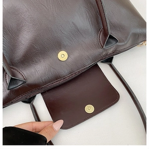 Macro detail of dark brown leather tote featuring dual zip and magnetic buckle closure