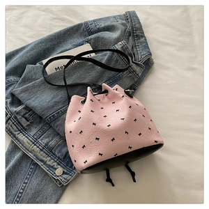 Detail of pink bucket bag with black bow patterns and elegant drawstring closure